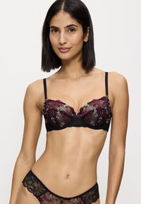 Soutien-gorge en dentelle noire avec broderies florales en magenta et argent, design à armatures, bretelles réglables, accompagné d'un slip en dentelle assorti.