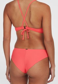Koraļļu bikini ar regulējamām siksnām un sasaistīšanu aizmugurē. Gluda, elastīga materiāla, ar minimālu apakšējo daļu segumu. Diskrets metāla detaļas.