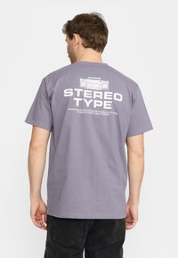 Grijze t-shirt met een relaxte pasvorm, voorzien van een boombox grafiek en de tekst "STEREO TYPE" in het wit op de achterkant. Korte mouwen, van katoen.