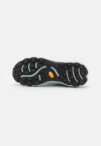 Shoe outsole featuring a black rubber base with a patterned tread, accented by light green side details and a yellow logo.