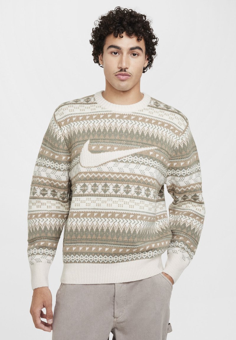Strickpullover in Creme, Grün und Braun mit geometrischen Mustern, gerippten Bündchen und Rundhalsausschnitt; auf der Vorderseite befindet sich ein dezentes Nike-Logo.