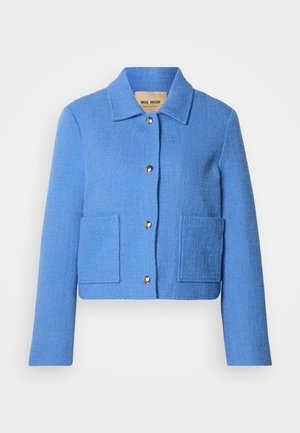 Kék, texturált, rövid fazonú dzseki klasszikus gallérral, elől gombos zárral és két foltzsebbel. Az anyagok szövött hatásúak, enyhe mintázattal.