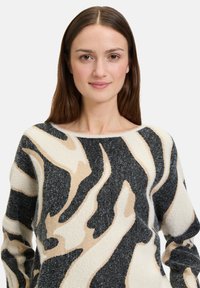 Gebreid sweatshirt met abstracte crème, zwarte en taupe golven. Zachte textuur met een wijde halslijn en lange mouwen.