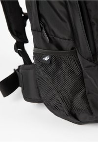 Black backpack featuring a textured nylon surface, mesh side pocket, and an adjustable strap. Notable brand logo displayed on the pocket.