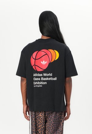 Black cotton t-shirt featuring three basketball illustrations in red, orange, and yellow. Text includes "Adidas World Class Basketball Exhibition" and location.