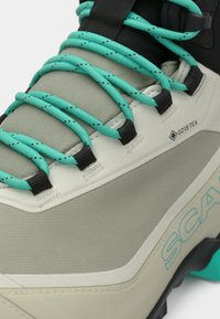 GORE-TEX matkajalatsid halli ülemise osa, türkiissiniste paelte ja mustade aktsentidega. Omab tekstuuriga materjali ja tugevat tallatüüpi, mis tagab haarduvuse.