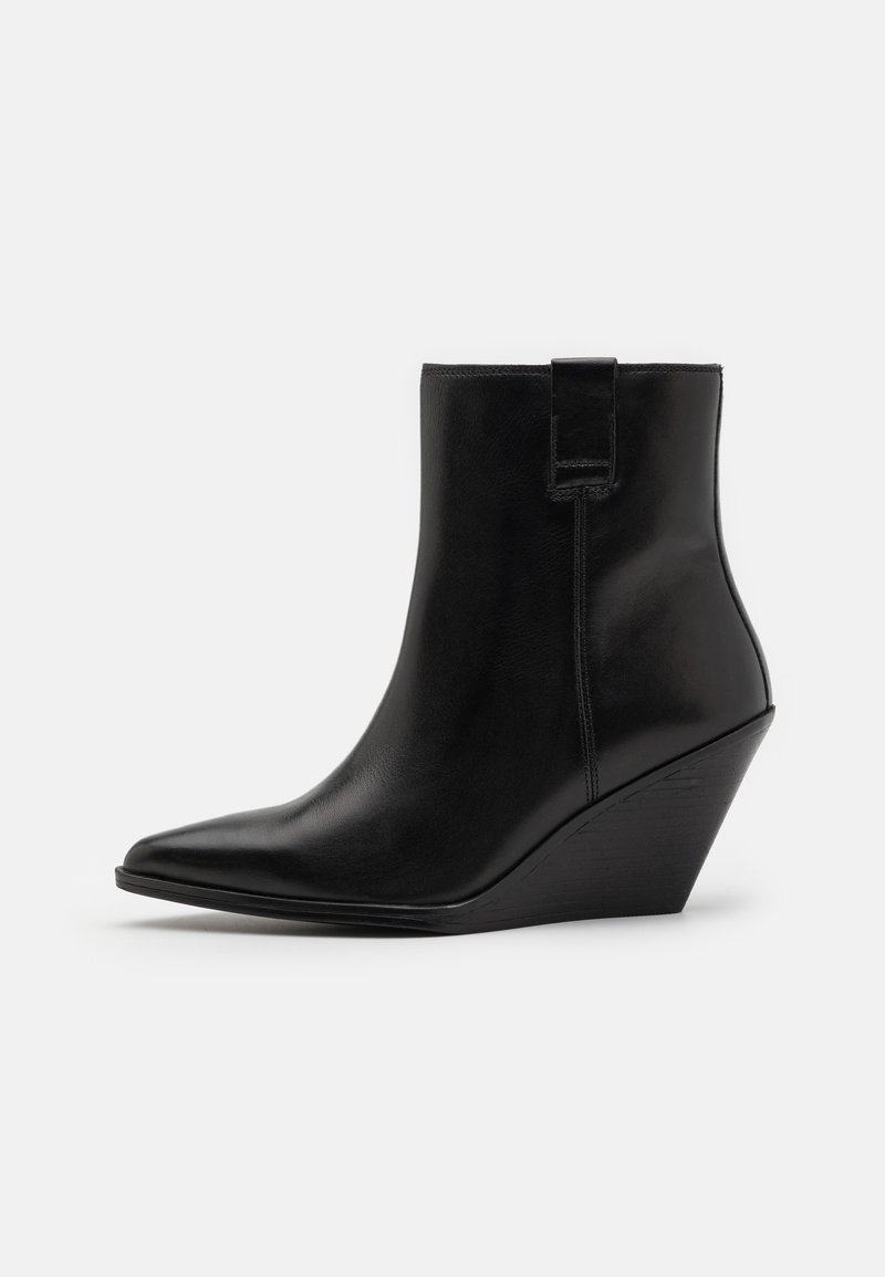Bottine noire en cuir avec un bout pointu et un talon compensé. Présente une texture lisse avec un onglet latéral et des détails de couture.
