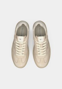 Beige Sneaker mit strukturiertem Wildleder-Obermaterial, rundem Zehenbereich und weißen Schnürsenkeln. Mit einem Logo auf der Zunge und einer hellbraunen Gummisohle. Größe 37.