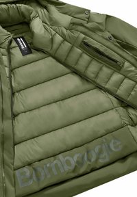 Giacca imbottita verde oliva con una superficie liscia, texture trapuntata, tasche con zip e un grande logo stampato sulla fodera interna.