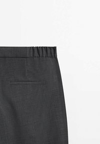 Pantalon gris foncé avec une ceinture élastique et une seule poche arrière horizontale sur un fond blanc.