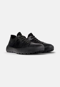 Zapatos deportivos negros hechos de cuero liso con un acabado texturizado, con cordones redondos y una suela de goma sólida con un patrón de relieve.
