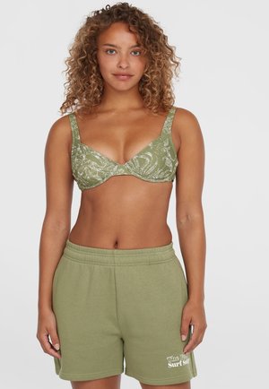Soutien-gorge vert à motifs avec des bretelles larges, offrant une texture douce. Associé à un short vert assorti avec une taille élastique et un détail de logo.
