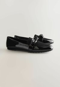 Sorte loafers med en shine læderfinish, overdel i ruskind og en dekorativ knude detalje henover forfoden. Flad gummisål for komfort.