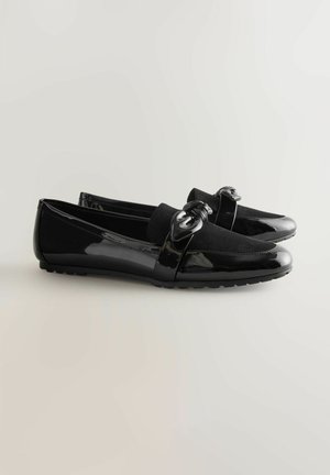 Černé loafers s lesklým koženým povrchem, semišovým svrškem a dekorativním uzlík s podélným detailem na nártu. Plstový gumový podpatek pro pohodlí.