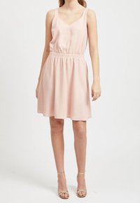 Jasnoróżowa sukienka bez rękawów z dekoltem w kształcie litery V, elastycznym pasem i spódnicą w kształcie litery A, wykonana z miękkiego materiału o gładkiej fakturze.