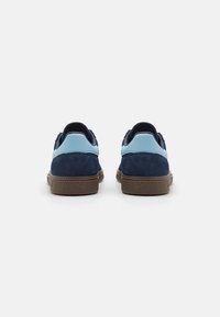 Navy suede shoes with light blue leather accents and brown rubber soles. Rounded shape with a textured pattern on the outsole.