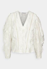 Blusa bianca con texture, scollo a V, maniche a campana, bordi arricciati e dettagli in pizzo. Il tessuto sembra leggero e semi-trasparente.