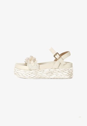White platform sandal with woven straw base, decorative braided detail on upper, and adjustable ankle strap with metallic buckle.