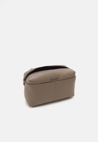 Kosmetyczna torba Calvin Klein w teksturowanej taupe z sztucznej skóry, z zamknięciem na zamek, zaokrąglonymi krawędziami, wytłoczonym logo z przodu i kompaktowym designem.