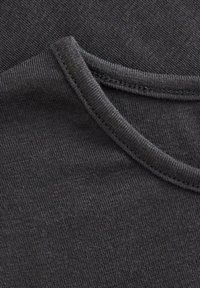 T-shirt in cotone nero con scollatura rotonda, texture fine e cuciture sottili lungo il collo. Tessuto liscio e resistente.
