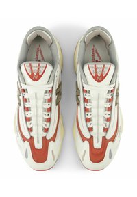 Weiße und rote Sportschuhe mit grauen Akzenten, aus Mesh- und Synthetikmaterialien, mit aufwändiger Nahtführung und einem auffälligen Logo.