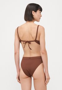 Brun ribbet bikini-set med justerbare stropper, en knytelukking og høyt liv med en glatt tekstur.