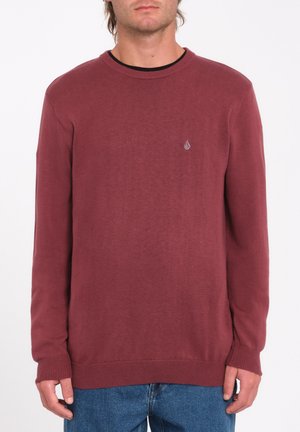 Pull col rond bordeaux avec des poignets et un ourlet côtelés, fabriqué en matériau tricoté doux, comportant un petit logo sur la poitrine.