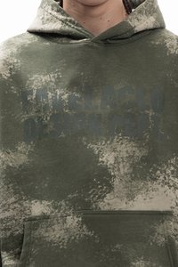 Olivově zelená mikina s kapucí z měkké látky, s texturovaným vzorem a předním kapsou; nápis "FAVELA CLO DESIGN DEPT." zřetelně viditelný.