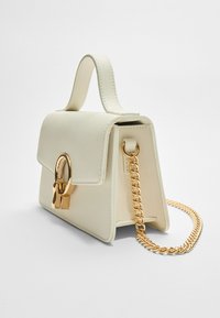 Cream handbag with a structured design, featuring a top handle, gold chain strap, and a gold lock hardware accent on the front.