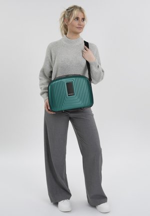 Tealfarbene Hartschalen-Schultertasche mit vertikaler Rillenstruktur, schwarzen Hardware-Akzenten und einem rechteckigen Fach. Glattes, langlebiges Material.