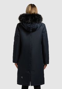 Piumino blu navy con cappuccio in pelliccia sintetica, maniche lunghe, tasche laterali e taglio dritto, caratterizzato da una chiusura a bottone all'orlo.