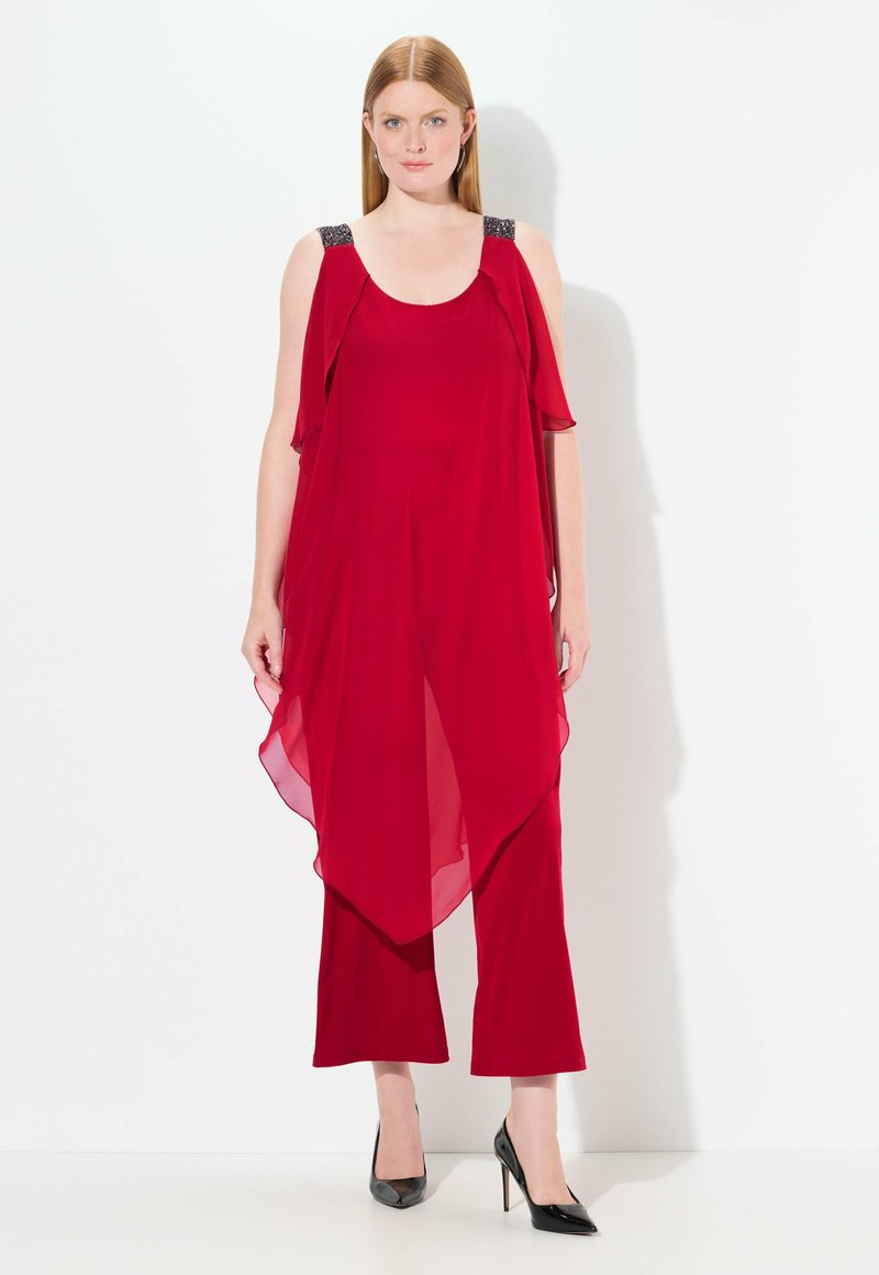 Mono rojo con superposición de chiffon fluido, piernas anchas y tirantes de hombro adornados. Textura suave y tejido ligero.
