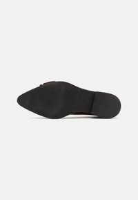 Scarpa rossa con punta a forma appuntita e tacco nero basso. Materiale superiore liscio con finitura opaca. La suola è robusta e piatta.