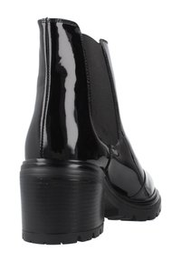 Botín de charol negro a la altura del tobillo, con paneles laterales elásticos, puntera redondeada y tacón grueso. Suela texturizada para un mejor agarre.