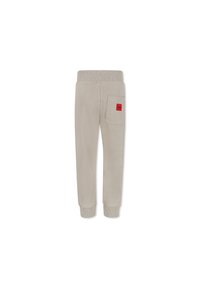 Pantalons de survêtement beige avec une taille côtelée et un ourlet resserré. Comprend une poche arrière avec une étiquette carrée rouge. Texture douce et lisse.