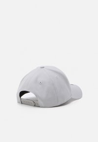 Grå caps med buet skjerm, myk stofftekstur, justerbar snapback-lukking og ventilasjonshull på baksiden.