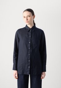 Marineblauwe linnen overhemd met een knopenlijst, puntige kraag, enkele borstzak en lange mouwen, met een gestructureerde afwerking.