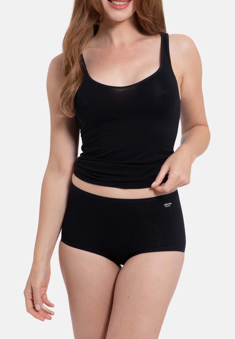 Top nera senza maniche con spalline sottili e un design aderente, abbinato a mutandine boyshort nere con un piccolo logo, entrambi realizzati in un tessuto liscio e elasticizzato.