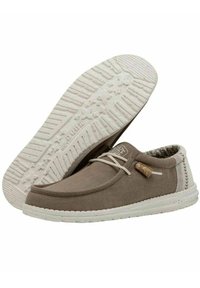 Scarpe in canvas marrone con suola in gomma bianca, dettagli in pizzo, accenti testurizzati e un'etichetta in sughero. Presentano un design cucito lungo i lati.