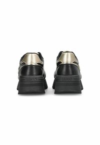 Sneaker nere con un design massiccio, caratterizzate da accenti in oro metallizzato e una suola in gomma testurizzata, dettagli di branding sulla parte posteriore e un tallone curvo.