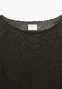 Donkergrijze gebreide trui met een ronde halslijn en een open weefpatroon. Etiket toont "Massimo Dutti Studio, Made in Spanje."