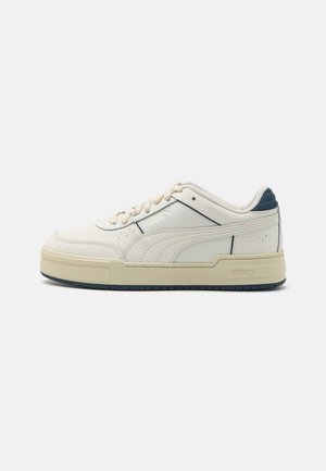 Lavtop hvid sneaker med cremefarvet sål, snørelukning foran, tekstureret læder sidebånd og navy ankelkravedetalje.