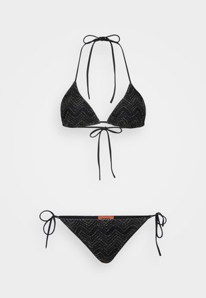Fekete bikiniszett, amely triánguláris nyakba akasztós felsővel rendelkezik, zig-zag mintázattal és kötelekkel, valamint a hozzá illő alacsony derekú bikini alsóval, szintén kötelekkel.