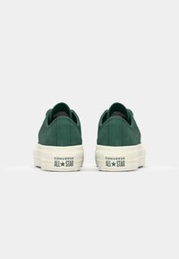 Grønne semskede sneakers med hvide gummisåler. Har et lavt design og "Converse All Star" branding på hælen.