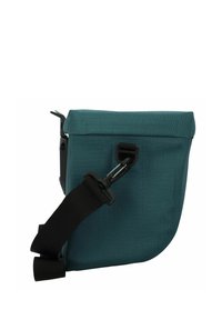 Borsa a spalla in tessuto teal con parte superiore pieghevole e tracolla nera regolabile. Presenta una chiusura a clip e una forma rettangolare strutturata.