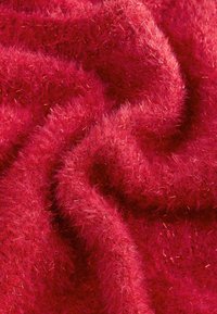 Crveni, pahuljasti tekstil s mekim teksturom i metalnim nitima. Tkanina ima valovit izgled s vizualnom dubinom i sjajem.