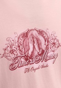 Lyserød bomulds t-shirt med et vintage grafisk design af sammenfoldede hænder med blomsterelementer og teksten "Tid er penge" i rødt.