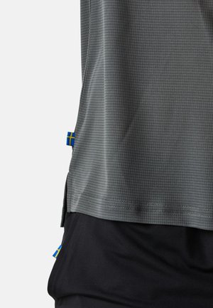 Graues Sporttrikot mit Karomuster, kurzen Ärmeln und blau-gelben Akzenten der schwedischen Flagge an den Seiten. Kombiniert mit schwarzen Shorts.