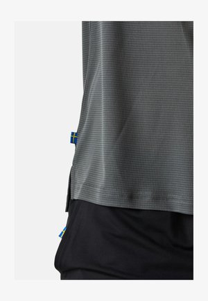 Grå idrottströja med ett rutmönster, korta ärmar och blå-gula svenska flaggdetaljer på sidorna. Matchad med svarta shorts.