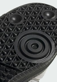 Suela de zapato negra con una superficie texturizada que presenta patrones en diamante, diseños circulares en relieve y un borde suave para una mayor tracción.